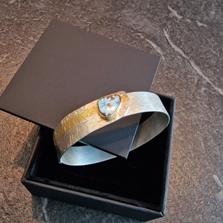 Handgeschmiedeter Armreif mit Boulder Opal in Silber und Feingold